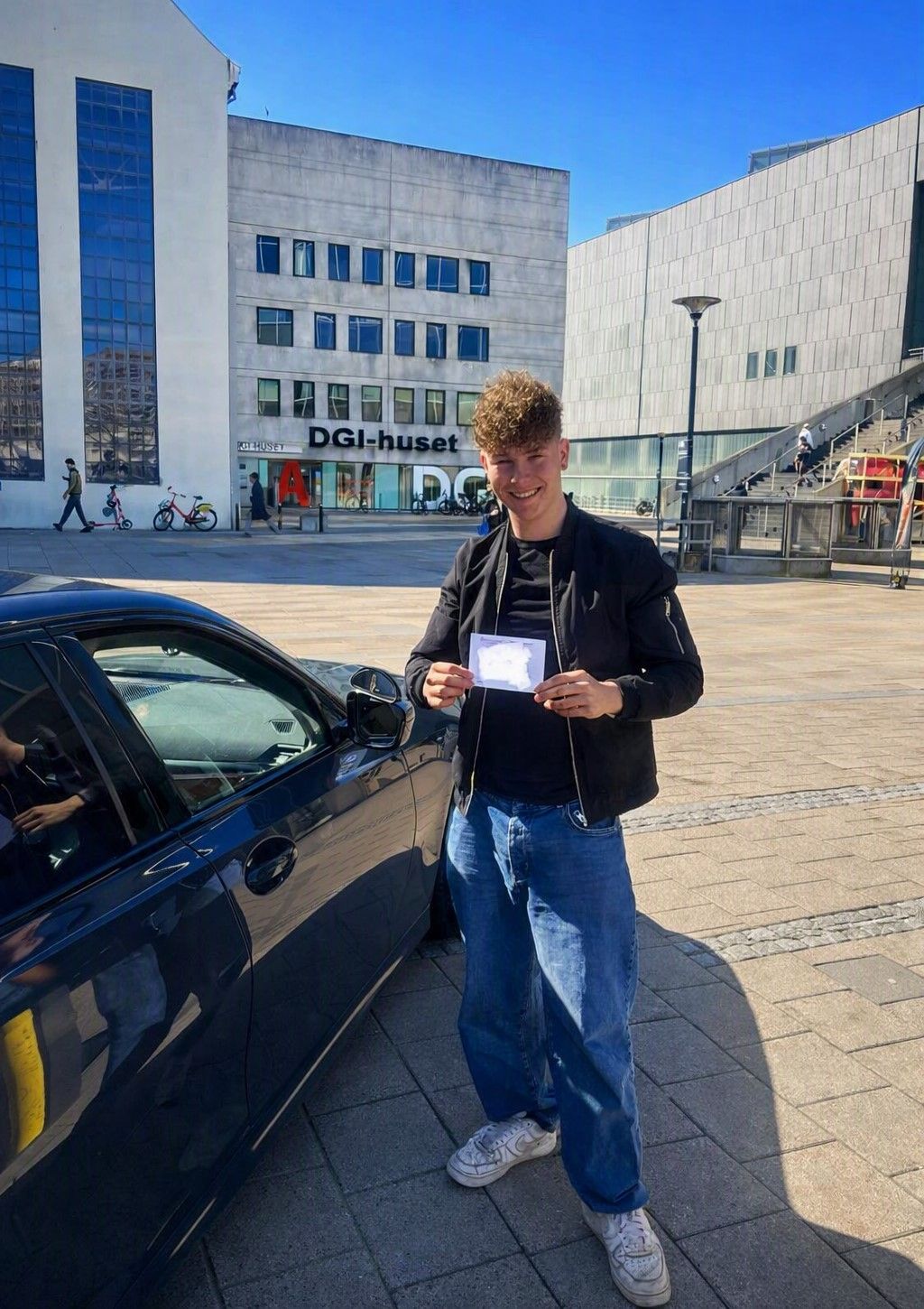 Bestået elev med sit kørekortbevis efter generhvervelse — foran DGI-huset og Bruuns Galleri i Aarhus