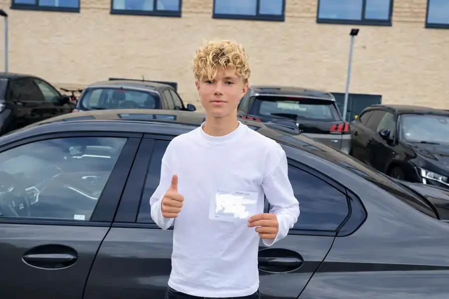 Bestået elev med tommelfinger op og kørekortbevis efter generhvervelse hos Andinas Køreskole i Aarhus